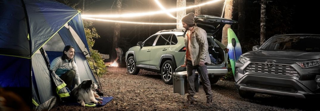 Couple with Two 2020 Toyota RAV4 Models on a Campsite at Night