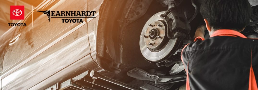 Mechanic Working on Brakes of a Car on a Lift with the Earnhardt Toyota Logo in Upper Left