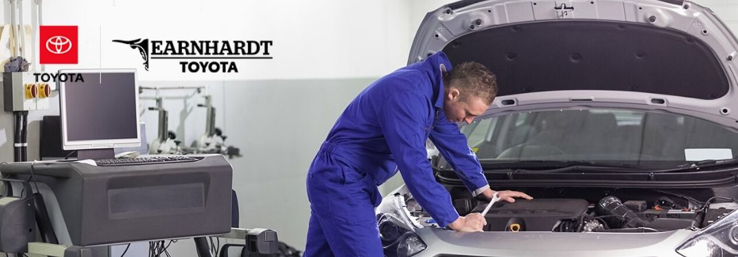 Mechanic Under the Hood of a Car with Earnhardt Toyota Logo in Upper Left Corner