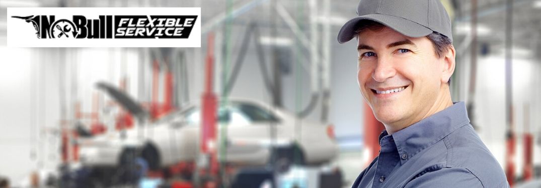 Smiling Mechanic in a Garage with Black No Bull Flexible Service Logo in Upper Left Corner