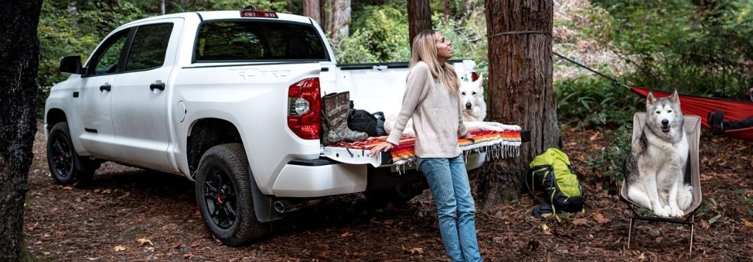 Woman, Dogs and White 2021 Toyota Tundra at a Campsite