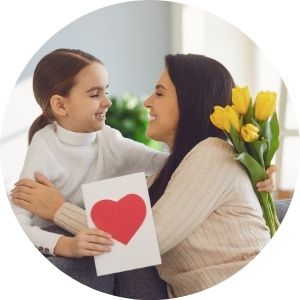 Mother and Daughter Hugging with a Card and Flowers
