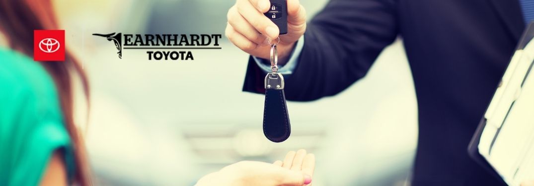 Dealer Handing Keys to a Woman and the Earnhardt Toyota Logo
