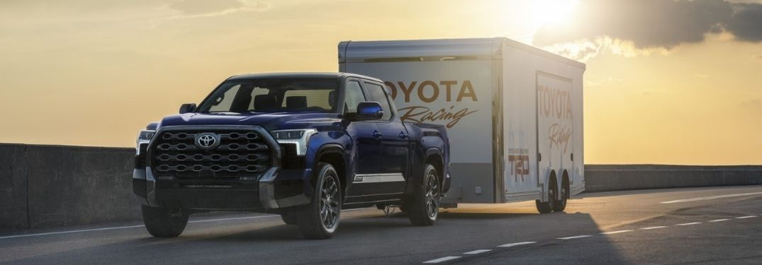 Blue 2022 Toyota Tundra Towing a Toyota Racing Trailer at Sunset