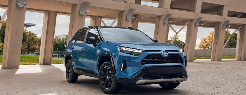 A blue 2022 Toyota RAV4 parked in front of an interesting building.