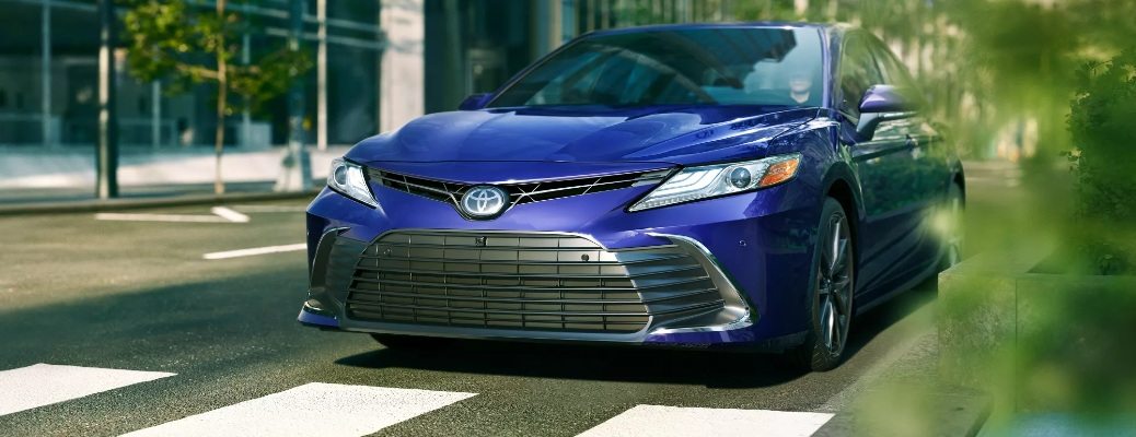 A blue 2022 Toyota Camry stopped at a crosswalk.