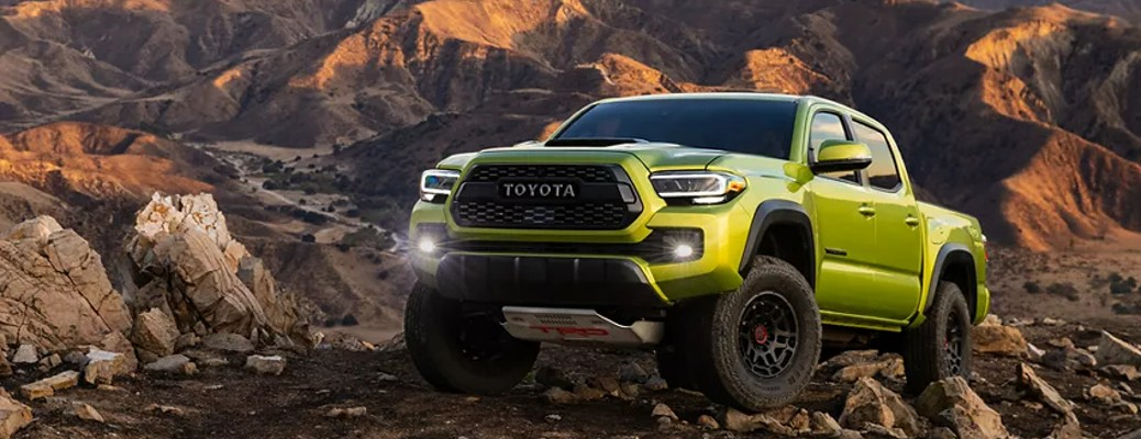 A 2022 Toyota Tacoma off-roading on rocky terrain, with arid mountains in the background