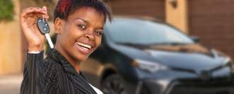 Person smiling, standing in front of a car, and holding car keys